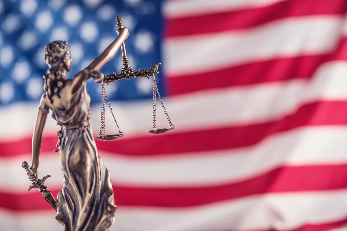 Statue of Lady Justice in front of an American flag
