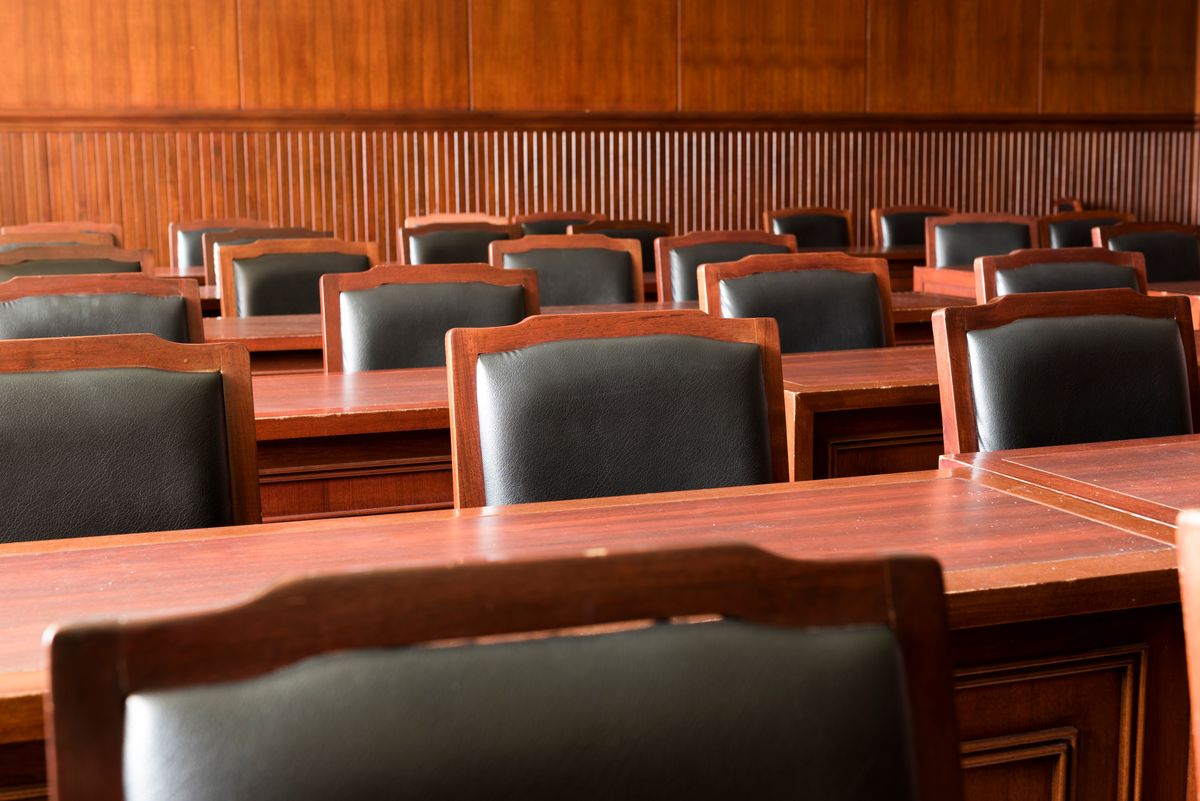 Rows of empty wooden chairs and tables in a courtroom
