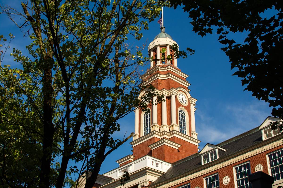 Red brick building with a tall white clock tower under a blue sky