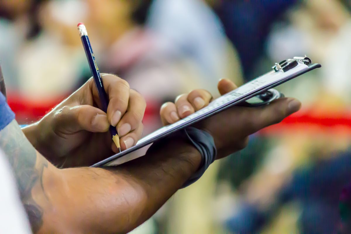 Hands writing on a form held on a clipboard