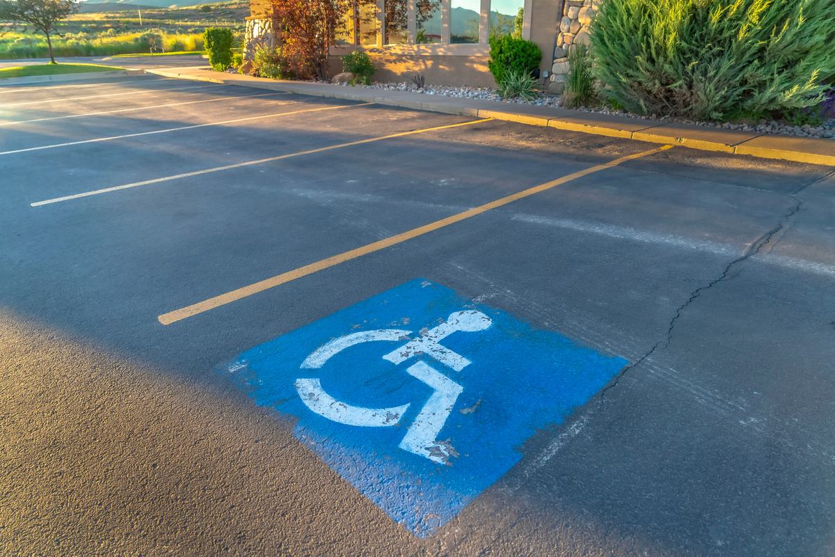 A blue accessible parking symbol painted on asphalt in a parking lot