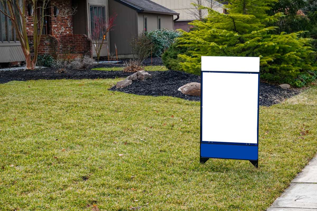 Blank sign standing in a lawn in front of a house