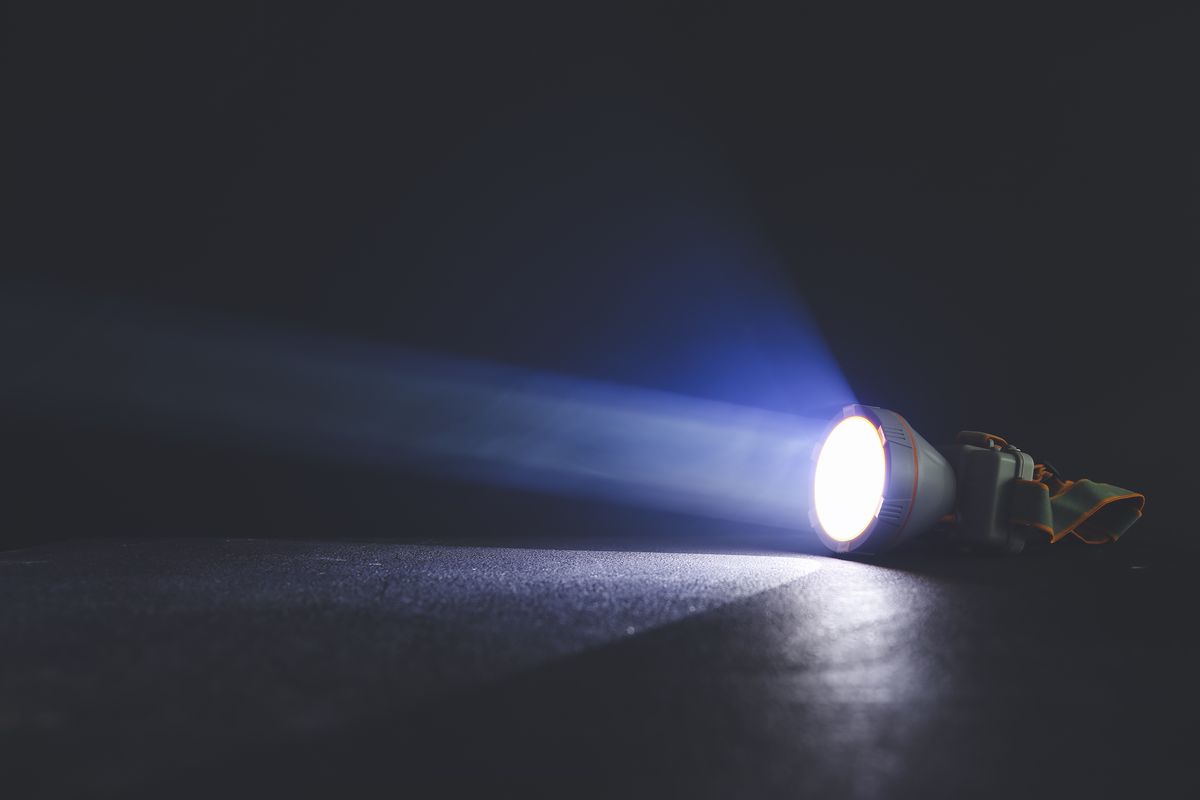 A flashlight shining a beam of light across a dark surface