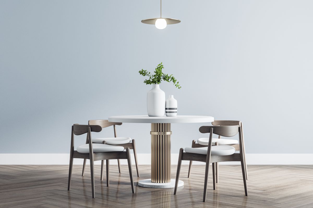 A round table surrounded by empty wooden chairs in a bright room
